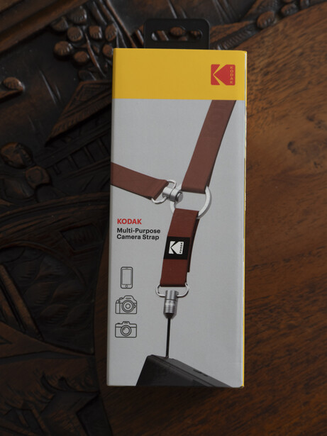 Kodak camera shoulder strap packaging displayed flat on a wooden surface.