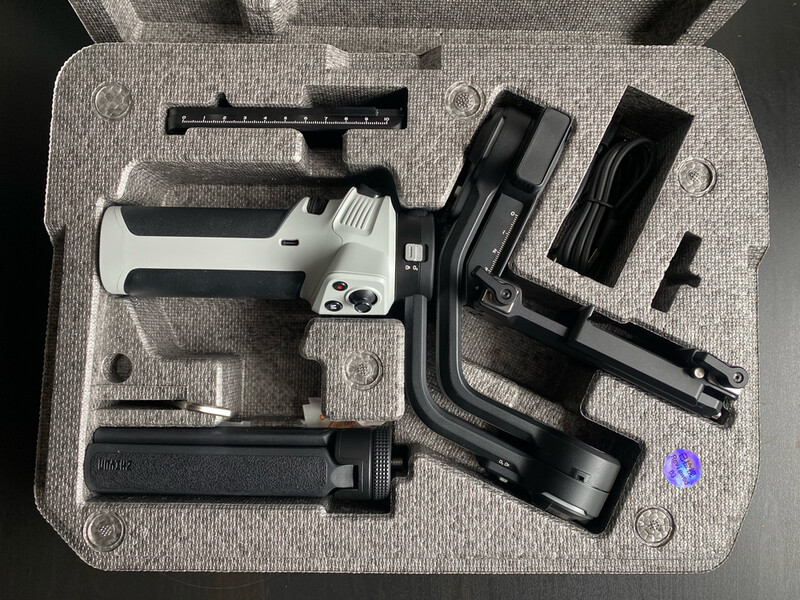 Gimbal stabilizer disassembled into component parts arranged on foam case interior.