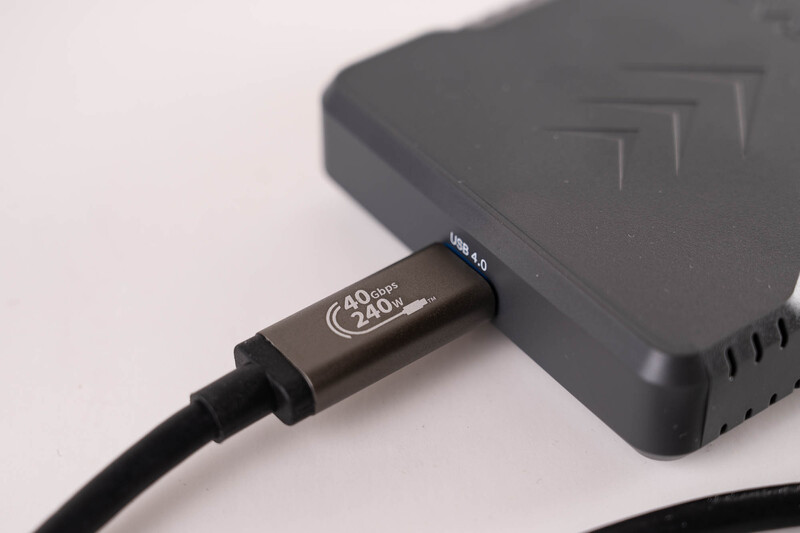 USB-C cable connected to a dark gray external hard drive against a white background.