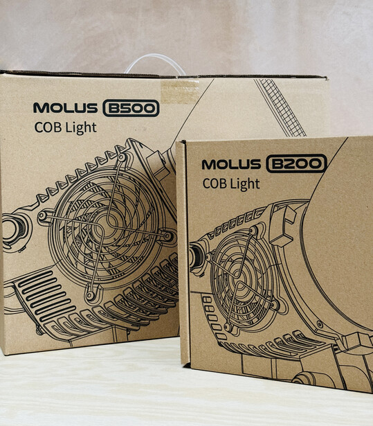 Two Molus B500 COB light product boxes displayed side by side, featuring technical line drawings of the lighting fixtures.