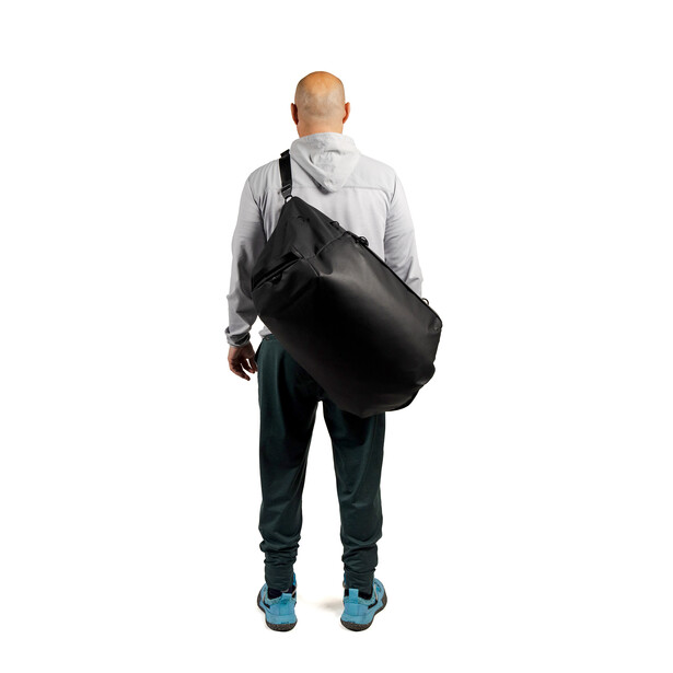 Man viewed from behind wearing a gray hoodie and black shoulder bag against white background.