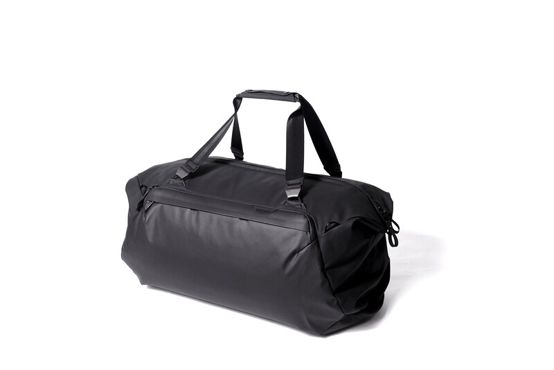 Black cylindrical duffel bag with dual handles and shoulder straps on white background.