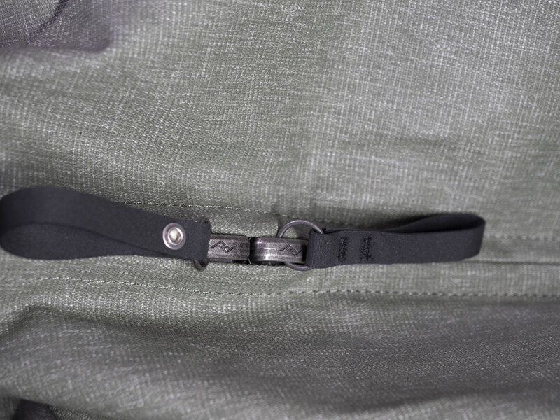 Black camera strap with plastic buckle and adjustment mechanism on gray fabric background.