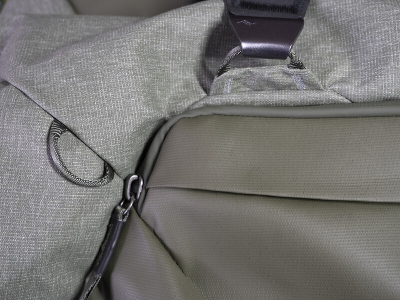 Close-up of a camera bag strap and zipper detail showing fabric texture and hardware attachment.