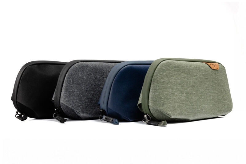 Four padded camera cases in black, gray, navy, and sage green arranged in a row.