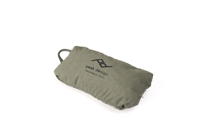 Compact travel pouch in sage green with waffle texture and carry handle, branded with logo.