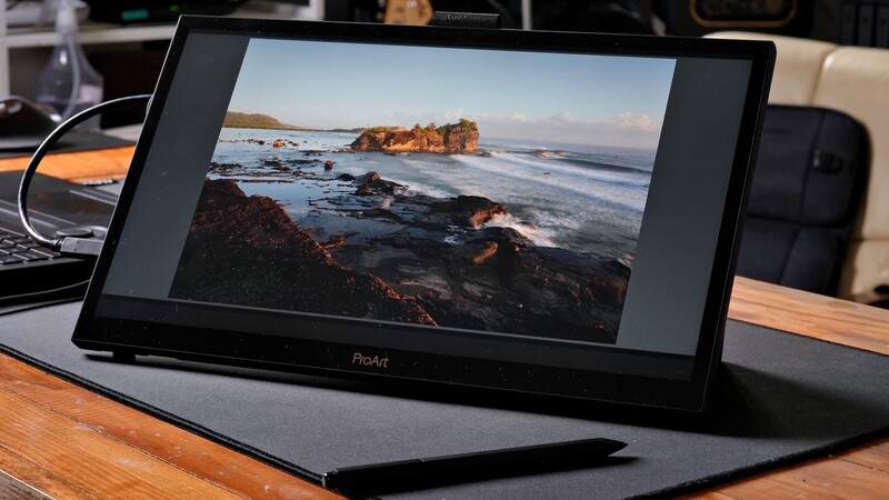 Portable display tablet showing coastal landscape photograph with rocky shoreline and golden-hour lighting.