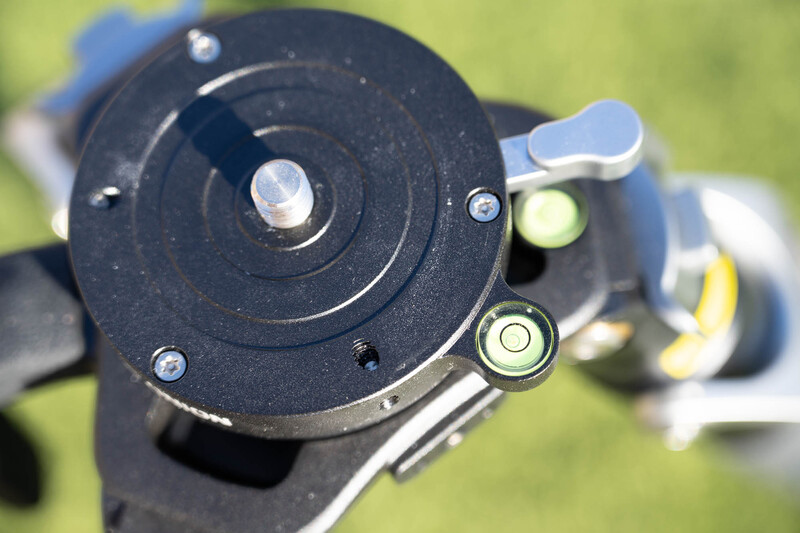 Close-up of a fluid head's top plate showing the central panning knob, adjustment controls, and spirit levels.