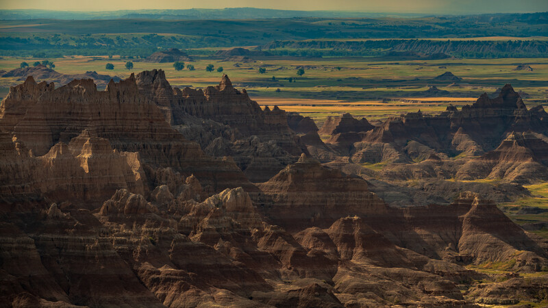 Dramatic badlands landscape with eroded rock formations and vast plains in the distance.