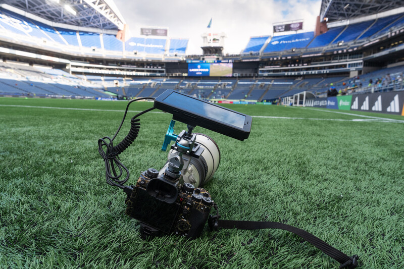 DSLR camera with external microphone on stadium grass field.