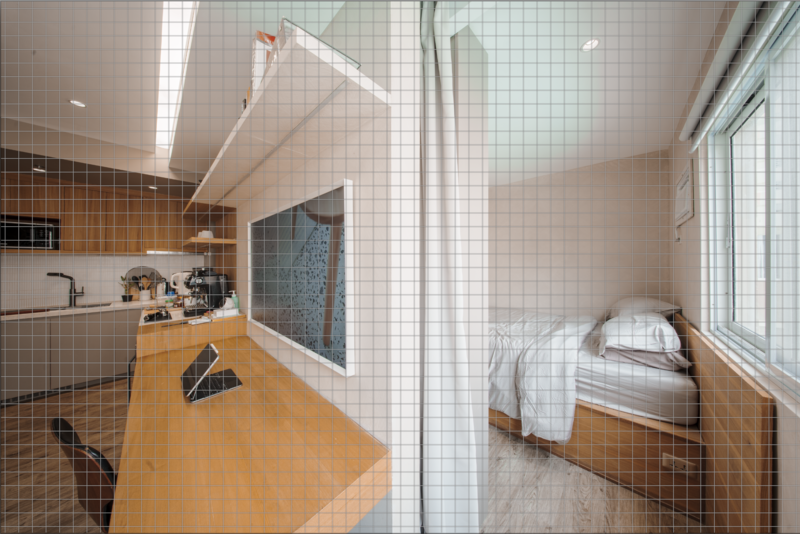 Overhead view of a compact bathroom and bedroom space with orange wooden flooring and white tile walls.