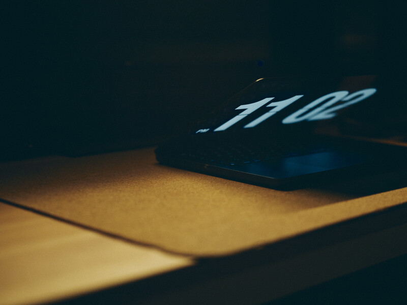 Dark camera or electronic device with illuminated buttons casting warm light on a yellow surface.