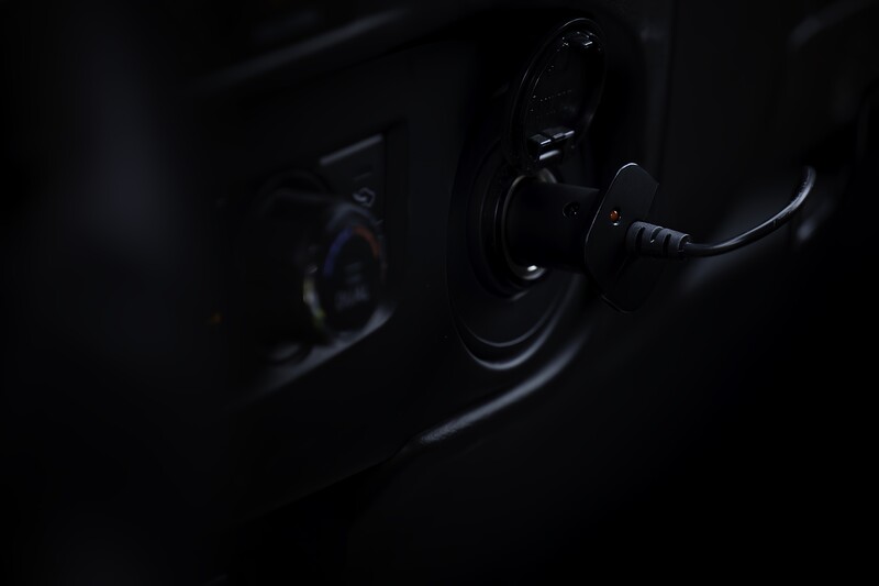 Close-up of bicycle pedal and crank arm illuminated against dark background.