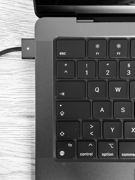 USB-C adapter connected to MacBook keyboard, photographed in black and white overhead.