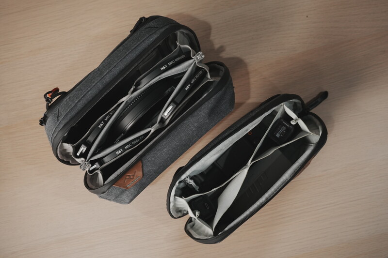 Two gray camera bags with black interiors displayed open on a wooden surface, showing their compartmented organization layouts.