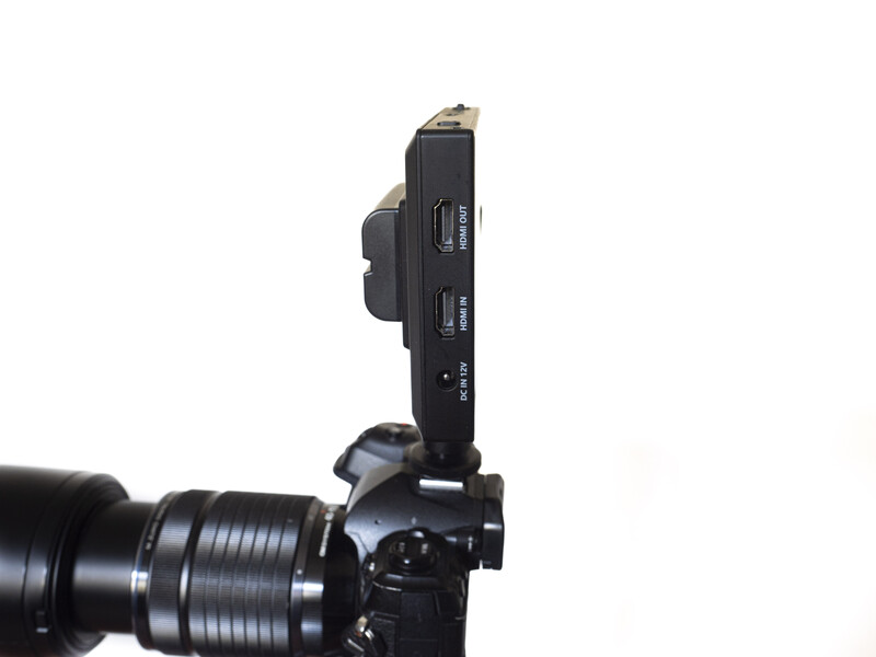 Wireless microphone receiver mounted on camera hot shoe above telephoto lens.