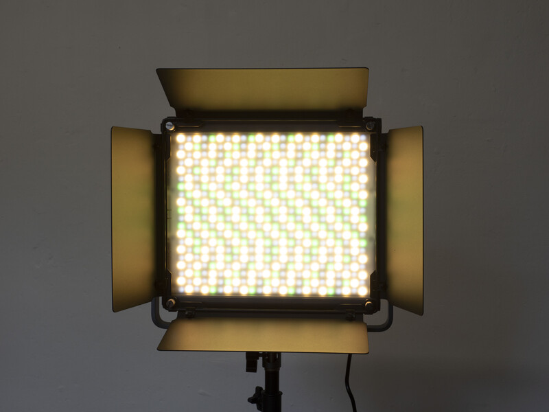 Professional LED panel light with barn doors and diffusion screen on stand against gray background.