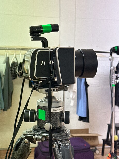 Cinema camera mounted on tripod with follow focus system and wireless video monitor.