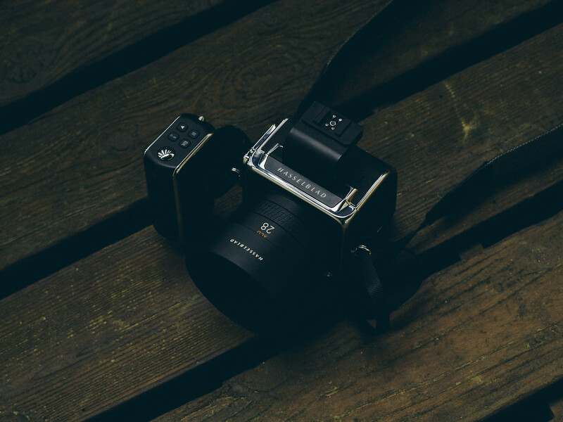 Vintage twin-lens reflex camera with light meter positioned on wooden surface with dramatic diagonal shadows.