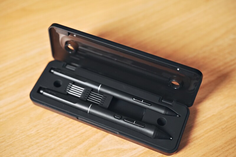 Black cleaning kit with brush tools and lens pen in open carrying case on wooden surface.