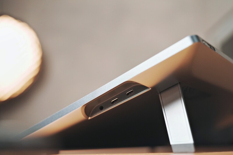 Smartphone with USB-C ports positioned at an angle on a stand with warm ambient lighting.