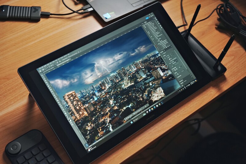 Tablet displaying aerial cityscape photo in editing software with adjustment panels visible.