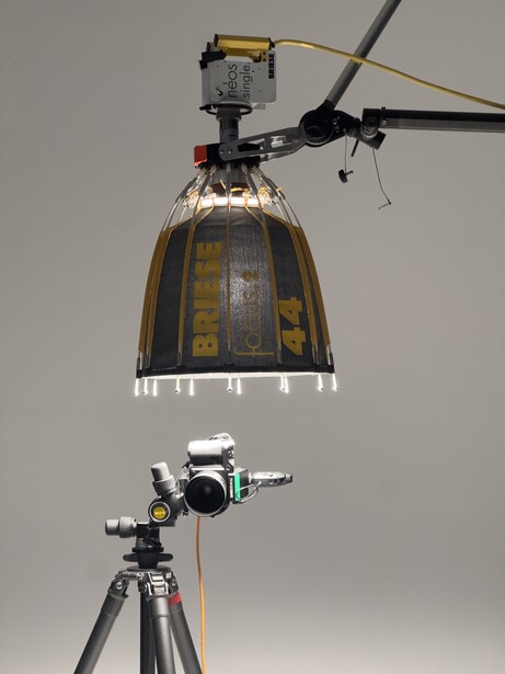 Lighting setup showing a helicopter hanging from a crane rig with a mounted camera and flash unit below.