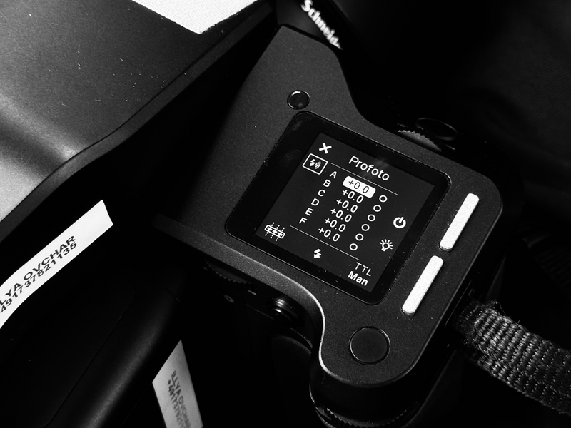 Close-up of a camera's external flash unit showing its LCD display screen and control buttons in black and white.