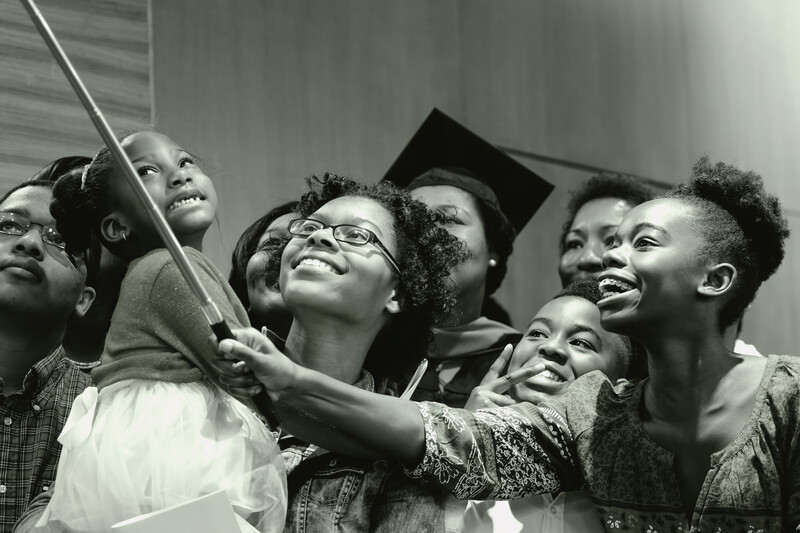 Group of people looking upward together, smiling, in black and white photograph.