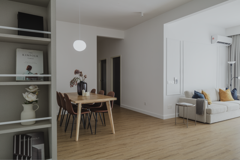 Modern apartment interior with light wood flooring, minimalist furnishings, and abundant natural light from large windows.