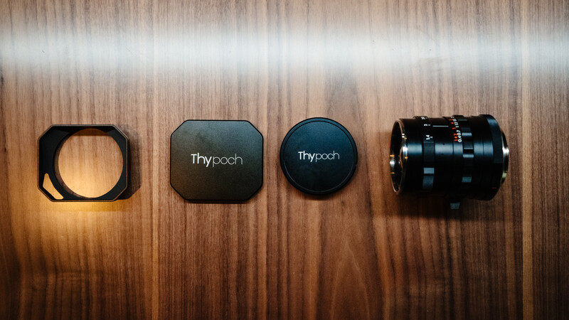 Four Thypoach camera accessories arranged left to right: lens hood, rounded case, circular lens cap, and macro lens extension tube on wood surface.
