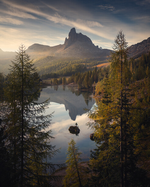 Mountain lake surrounded by coniferous forest with dramatic peak reflected in still water.