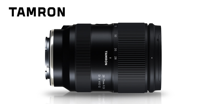 Tamron zoom lens with textured black barrel and focus ring against white background.