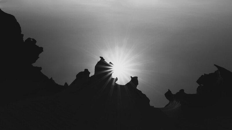 Silhouetted figures against bright backlit sky with dramatic rays of light.