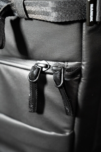 Close-up of two carabiners clipped to a gray fabric bag with stitched seams and straps.