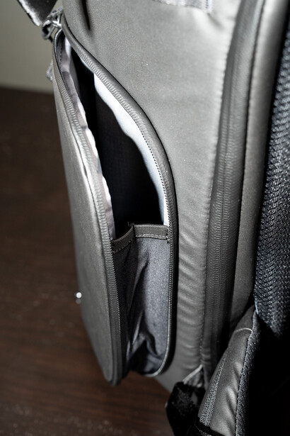 Gray camera bag with open side compartment revealing black interior storage space.