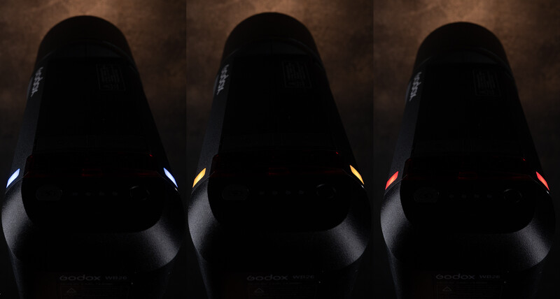 Three gaming chairs shown in profile against a brown textured backdrop, each illuminated by different colored accent lighting: white, yellow, and red.