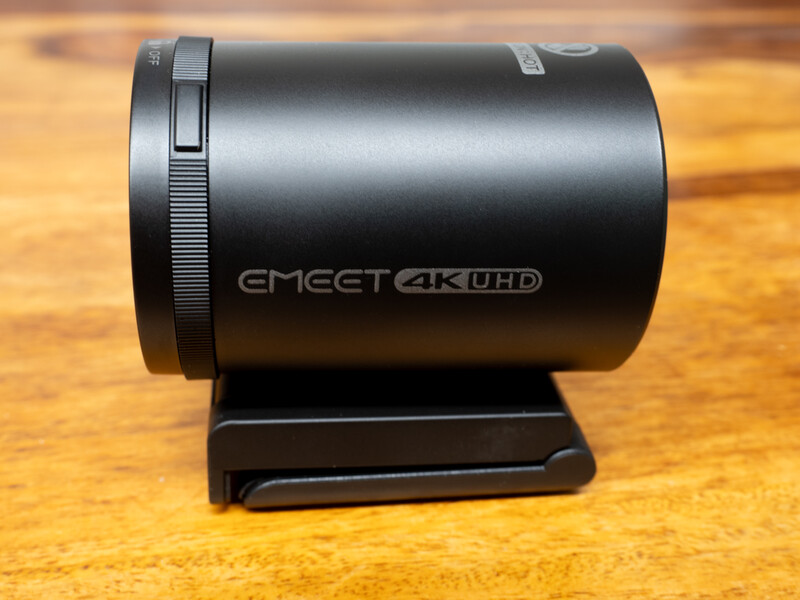 EMEET 4K UHD cylindrical action camera with mounting bracket on wooden surface.