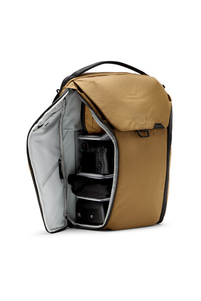Tan camera backpack with side panel open revealing black dividers and camera compartments.