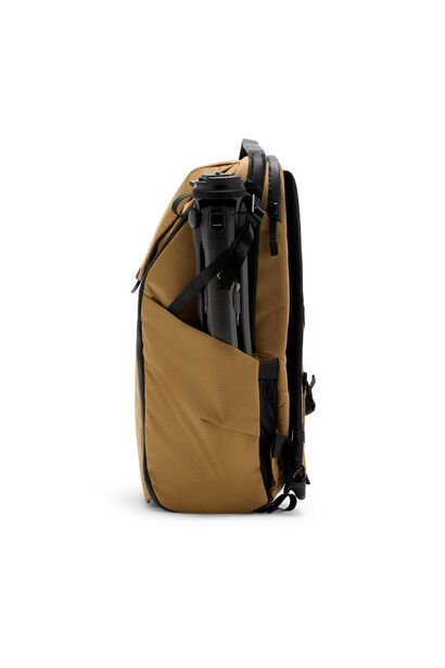 Tan and black camera backpack photographed from the side against a white background.