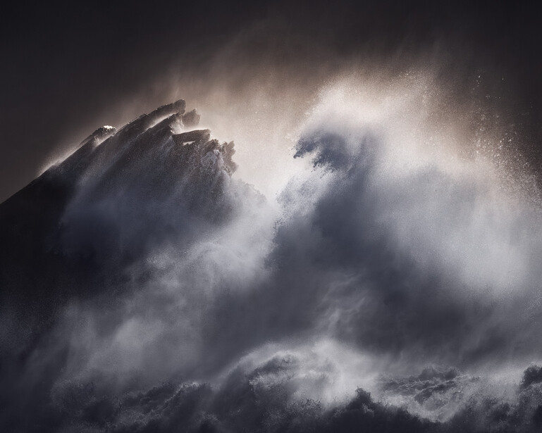 Dramatic mountain peaks shrouded in swirling mist and clouds against a dark sky.