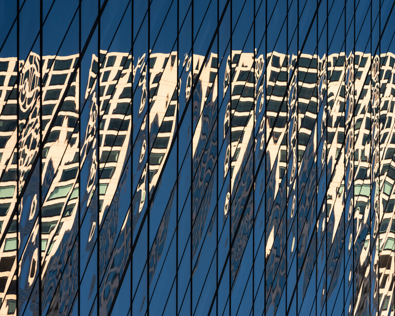 Geometric shadow pattern cast by vertical structures across a blue surface.