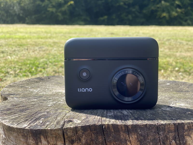 Llano compact action camera with lens and control dial sitting on weathered wood stump.