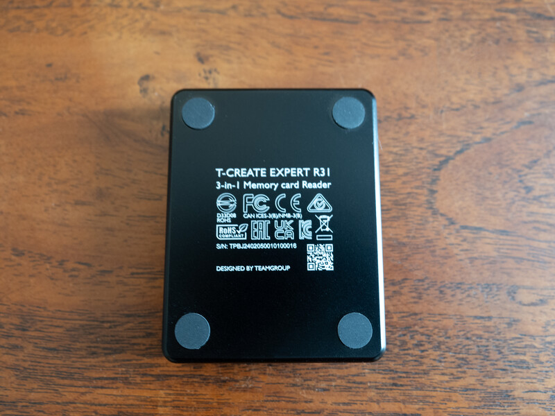 T-Create Expert R31 3-in-1 memory card reader with four rubber feet, shown from above on a wooden surface.