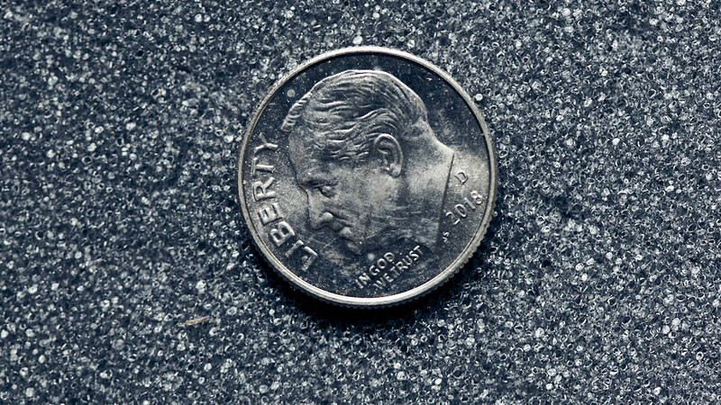 Silver coin with profile portrait facing left against textured gray background.