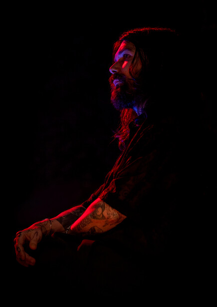 Arm and hand illuminated by red and blue neon lighting against a black background.