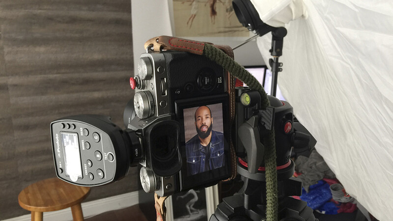 Vintage film camera displaying a man's face on its screen, surrounded by lighting equipment and accessories in a studio setting.