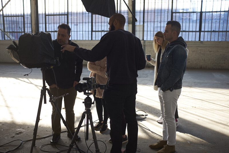 Film crew operating professional camera equipment on a rooftop location during daytime shoot.