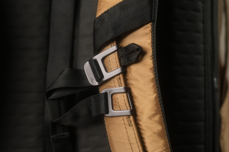 Black nylon straps with metal buckles securing a tan leather panel against dark fabric.