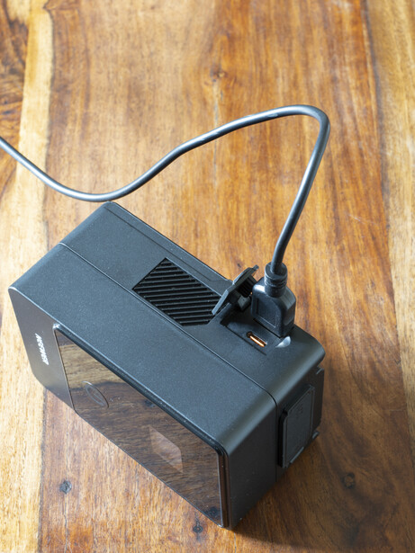 External hard drive with attached power cable on wooden surface.